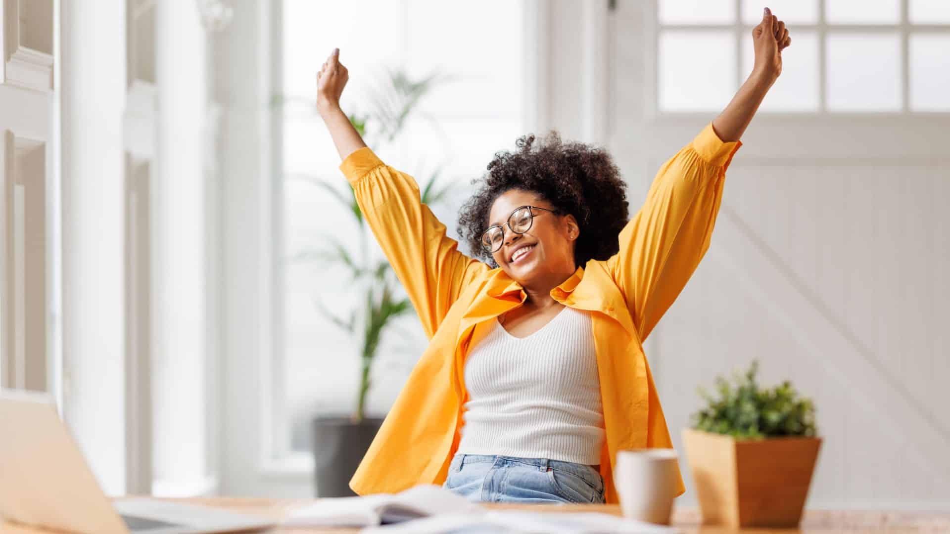 Business woman freelancer entrepreneur smiling and rejoices in victory while sitting at desk 1